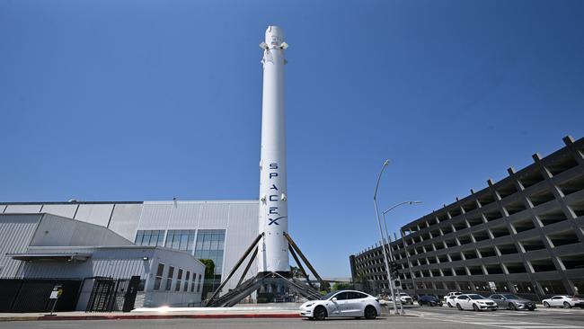 A driver in a Tesla drives past the Falcon 9 Booster at SpaceX Headquarters in Hawthorne, California. Picture: AFP