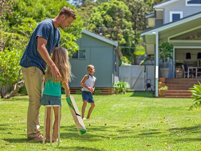 Kids playing cricket in their backyard.