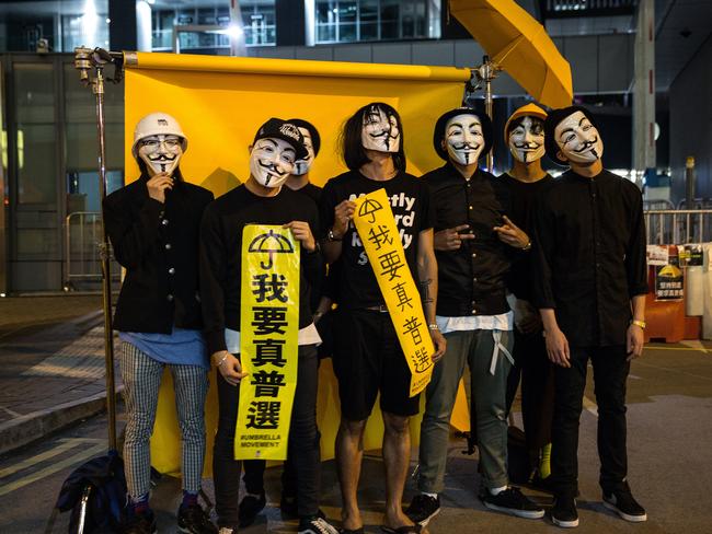 Masked protesters stand against a backdrop at a makeshift studio in Hong Kong. Picture: Getty Images