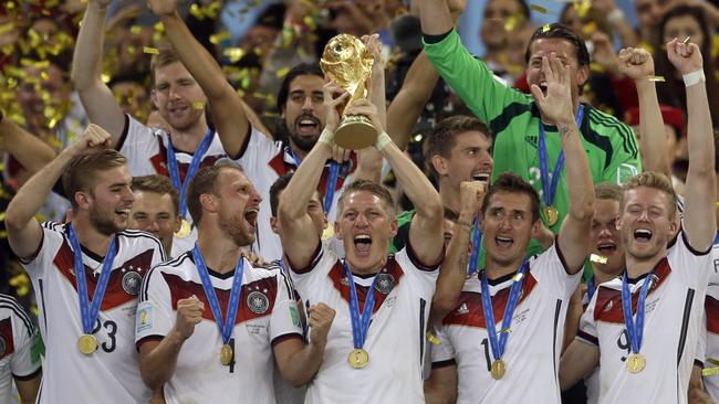 Bastian Schweinsteiger holds up the World Cup trophy as his teammates celebrate their 2014 triumph.