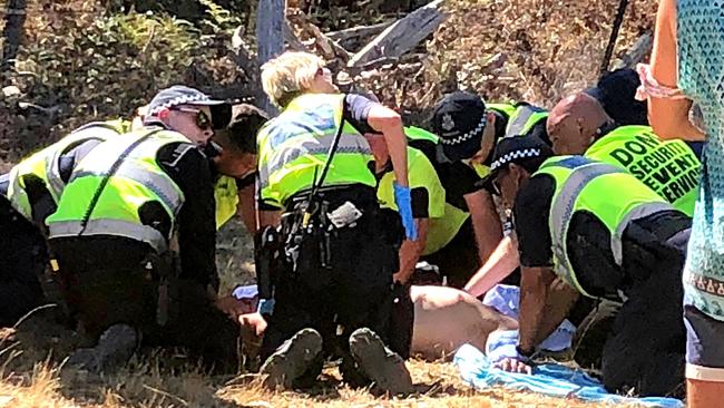 Emergency services attend a man before he is loaded into an ambulance.