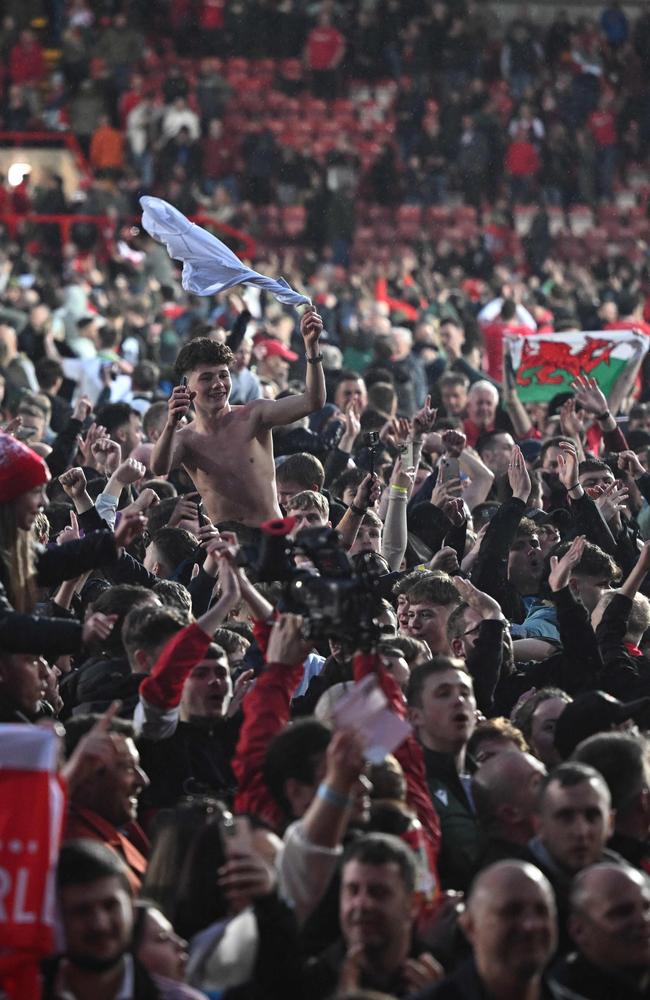 Wrexham's fans celebrate on the pitch. Photo by Oli SCARFF / AFP.