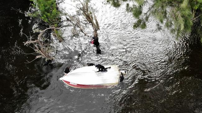 Police divers attend to the overturned boat. Picture: Toby Zerna