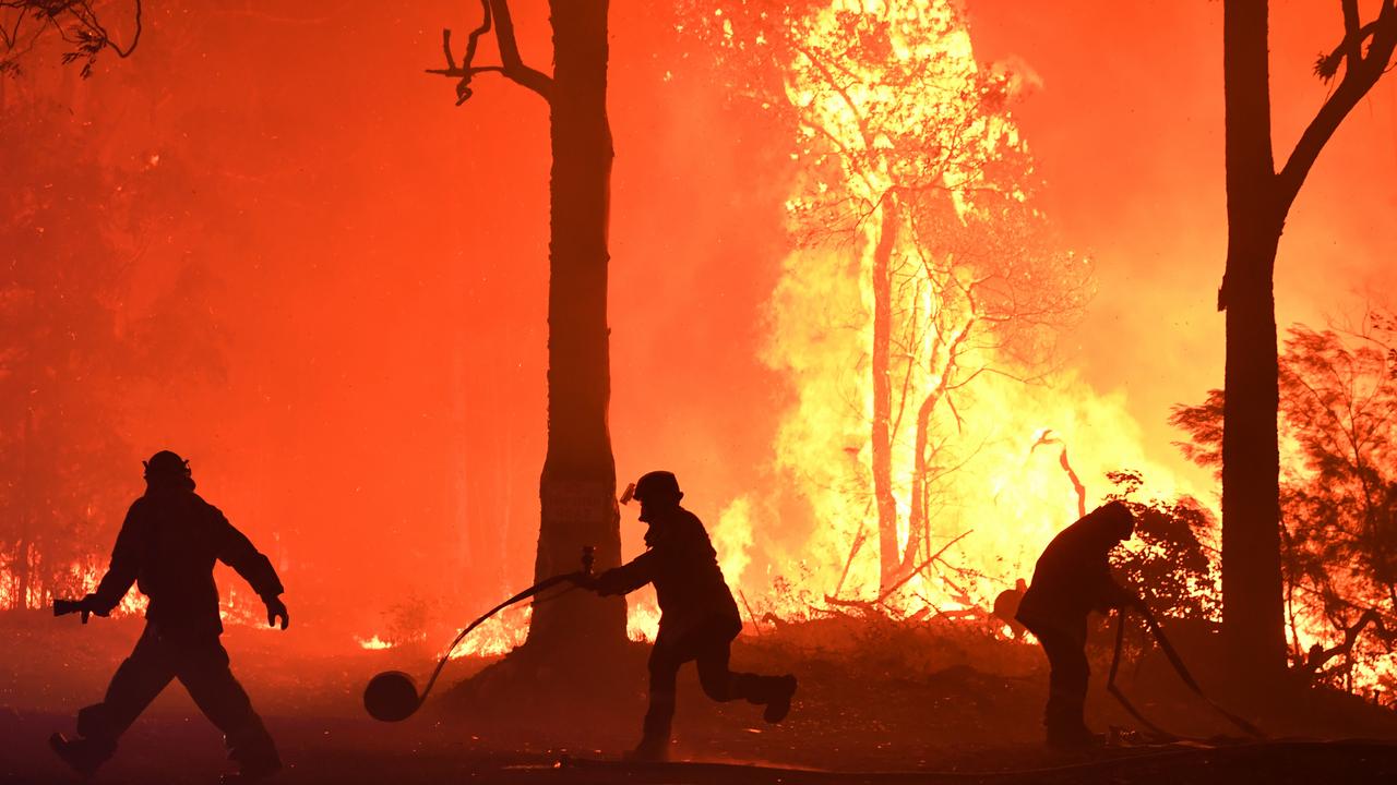 RFS volunteers and NSW Fire and Rescue officers fight a bushfire encroaching on properties near Termeil on the Princes Highway between Batemans Bay and Ulladulla. Picture: AAP Image/Dean Lewins