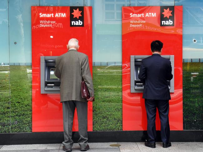 Two people use National Australia Bank (NAB) ATMs in Melbourne on May 2, 2019, as the NAB revealed that in the last six months it had put aside 368 million US dollars for 