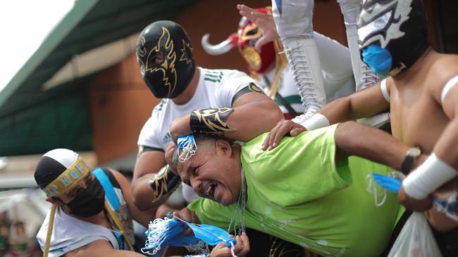 Mexican Lucha Libre wrestlers recreate a fight with a person who is not wearing a face mask on the street as part of a local campaign to promote the use of face masks. Picture: Getty