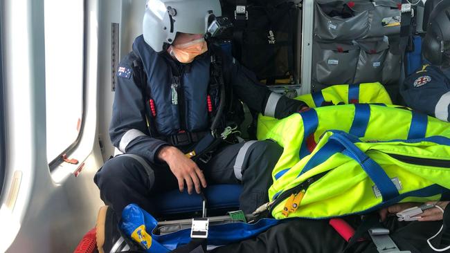 A rescue helicopter winched a seafarer up after suffering a suspected internal infection. PHOTO: RACQ Capricorn Rescue