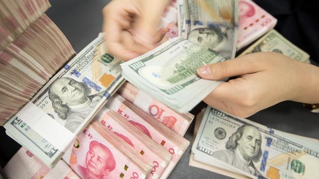 A Chinese bank employee counts 100-yuan notes and US dollar bills at a bank counter in Nantong in China's eastern Jiangsu province. Picture: AFP