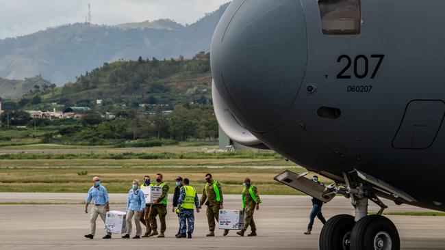 The Australian Medical Assistance Team unloads the vaccines with the assistance of Australian Defence Force staff based in Papua New Guinea.