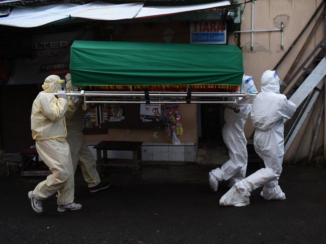 Health workers remove the body of a man who died of Covid-19 coronavirus at his Home in Bandung, Indonesia. Picture: AFP