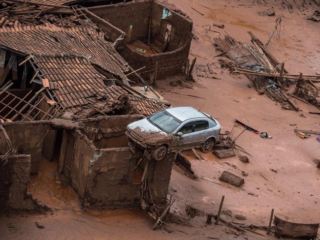 (FILES) Aerial view taken on on November 6, 2015, shows the covered in mud village of Bento Rodrigues, in Mariana, the southeastern Brazilian state of Minas Gerais, following the burst of a dam, at a mining waste site, of the company Samarco, jointly owned by Vale of Brazil and BHP, unleashing a deluge of thick, red toxic mud. A long-awaited trial into whether Anglo-Australian miner BHP is liable for one of Brazil's worst environmental disasters, which could trigger compensation totalling billions of dollars, opens in London on October 21, 2024. The High Court in London will over several months examine whether BHP was in part responsible for the collapse in 2015 of a tailings dam in Brazil that killed 19 people and caused huge environmental damage. (Photo by Christophe SIMON / AFP)