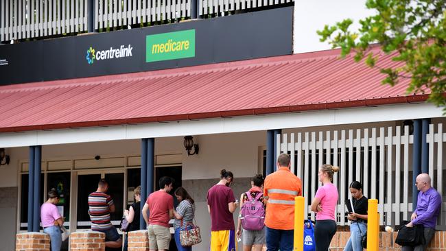 People are seen in a long queue outside a Centrelink office in March 2020. Centrelink offices around Australia were inundated with people attempting to register for the Jobseeker allowance in the wake of business closures due to the COVID-19 pandemic. (AAP Image/Dan Peled)