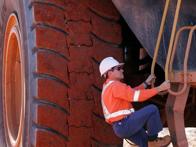 A worker climbs a ladder to enter the cab of a large ore moving truck at the Telfer Mine in the Pilbara region of Western Australia, Thursday, July 28, 2005. Newcrest Mining Ltd., the biggest Australian gold miner, has yet to decide whether to invest in the development of the A$1 billion ($755 billion) Boddington gold mine in Western Australia. Photographer: Will Burgess/Bloomberg News.