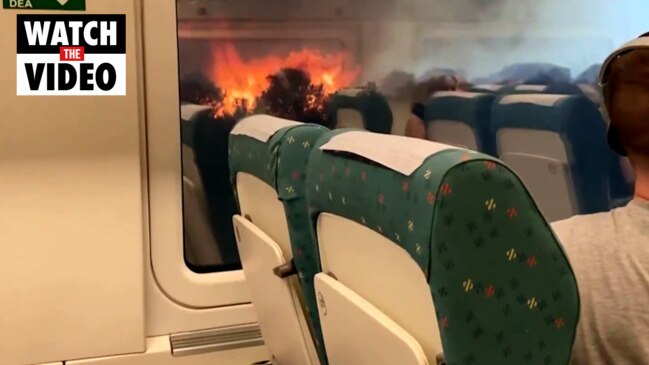 Passengers look on as wildfire rages near stuck train