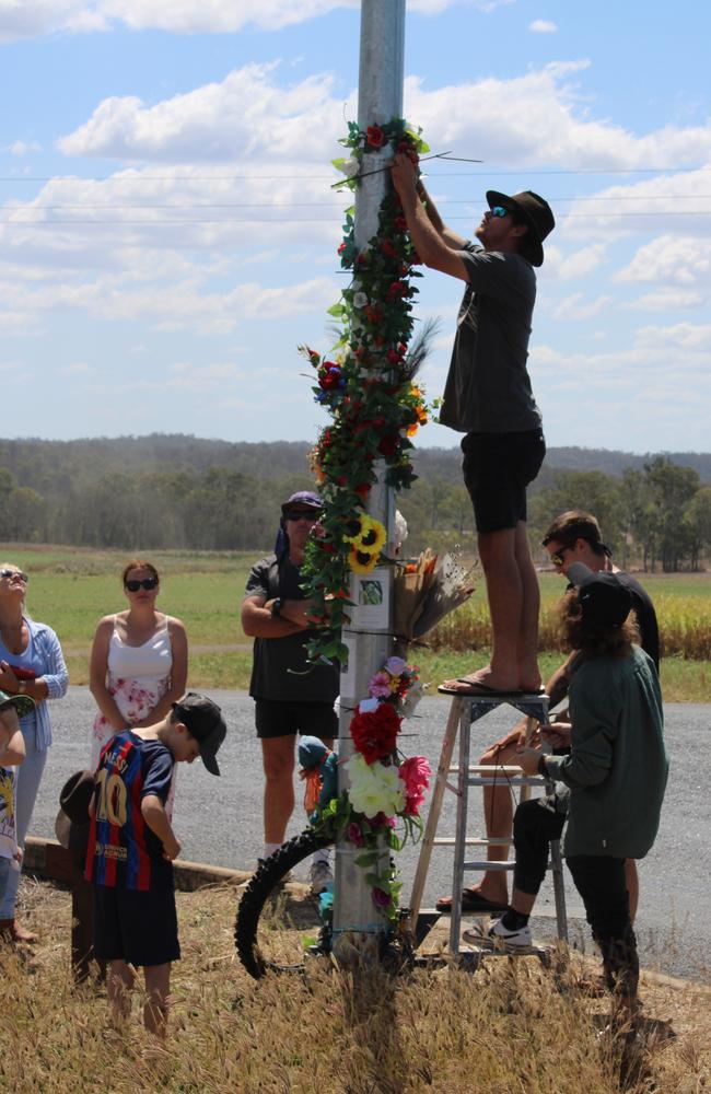 Family and friends wrap flowers around the lamppost at the corner of the crash scene.