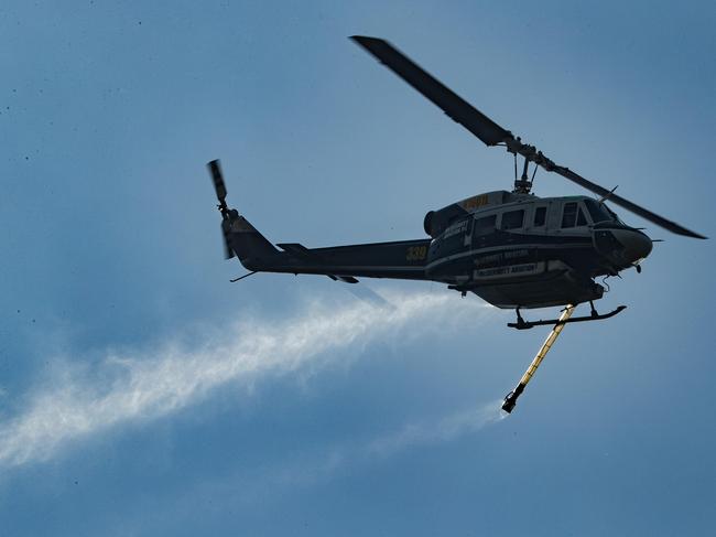 A water bombing helicopter works to contain a bushfire at Beerwah on Sunday afternoon. Picture Lachie Millard