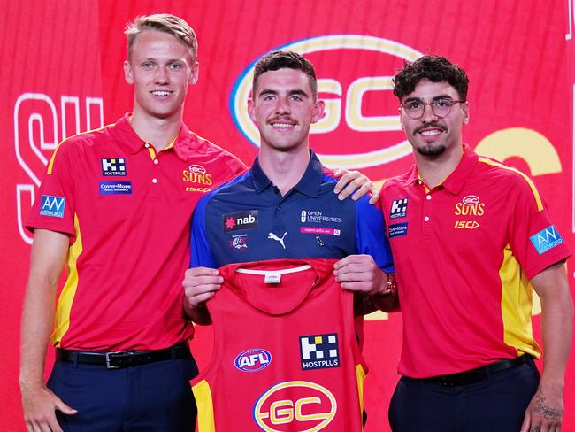 Sam Flanders is presented with a jersey by Jack Lukosius (left) and Izak Rankine of the Suns (right) during the first round of the 2019 AFL Draft at Marvel Stadium in Melbourne, Wednesday, November 27, 2019. (AAP Image/Michael Dodge) NO ARCHIVING