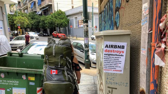 A tourist and Airbnb user walking past an anti-Airbnb posted in Greece. Picture: iStock