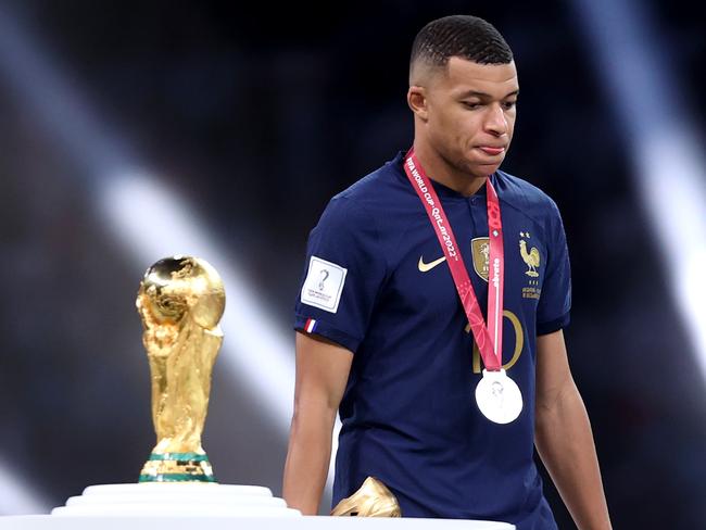 LUSAIL CITY, QATAR - DECEMBER 18: Kylian Mbappe of France walks past the FIFA World Cup Qatar 2022 Winner's Trophy during the awards ceremony after the FIFA World Cup Qatar 2022 Final match between Argentina and France at Lusail Stadium on December 18, 2022 in Lusail City, Qatar. (Photo by Julian Finney/Getty Images)