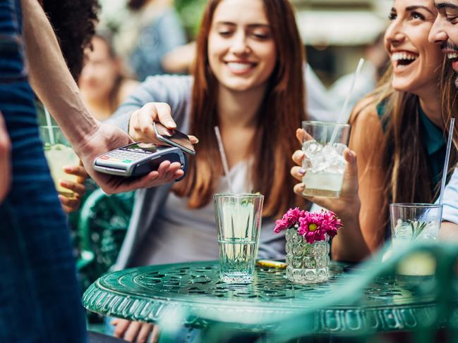 Young people in a cafe making a contactless payment through a mobile phone