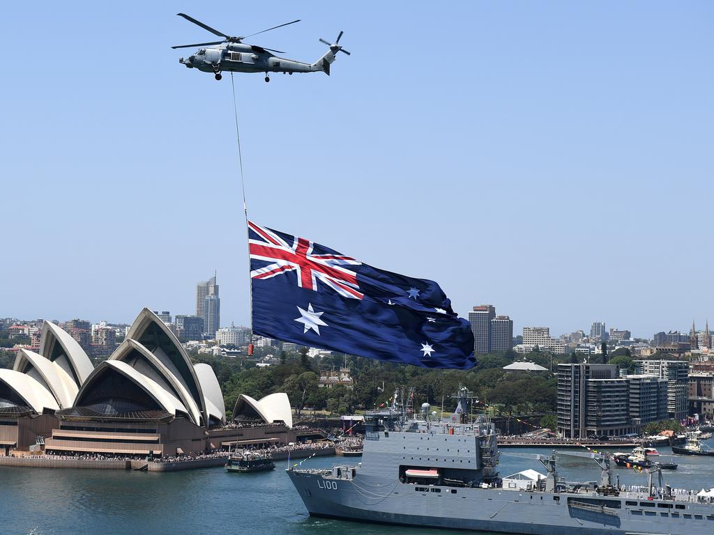 A Royal Australian Navy MH-60R Seahawk helicopter flies an Australian flag over Sydney Harbour during Australia Day celebrations in Sydney in 2019. Picture: AAP/ Dan Himbrechts