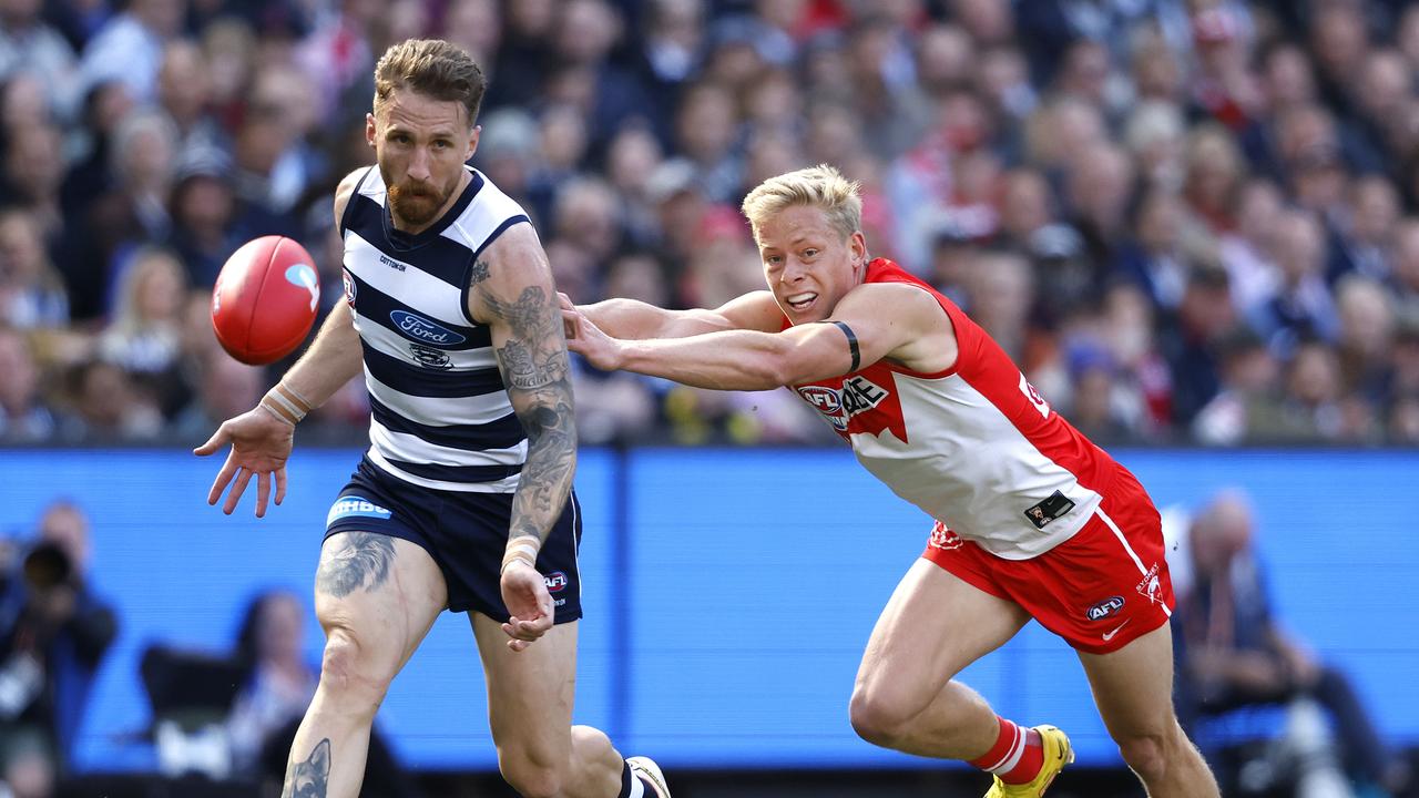 Geelong’s Zach Tuohy gets a kick away from a chasing Isaac Heeney. Picture: Phil Hillyard