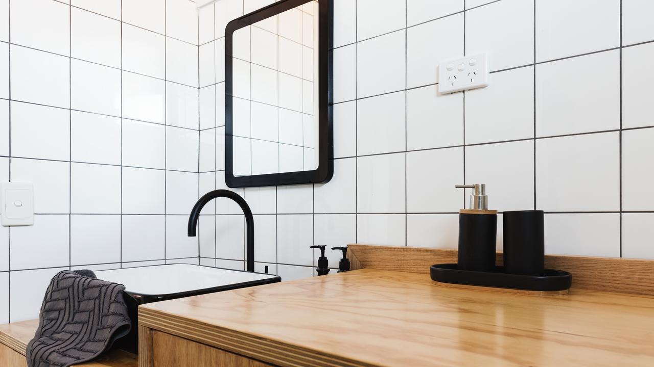 Contemporary bathroom with vanity of wood, black basin and taps