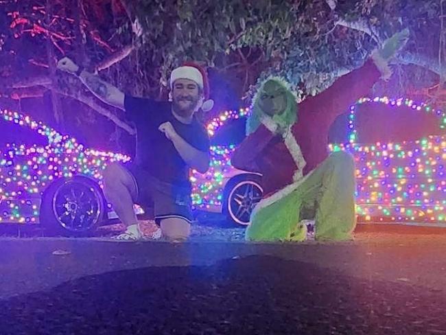 Hayden McIntyre and the Grinch pose in front of their festive vehicles