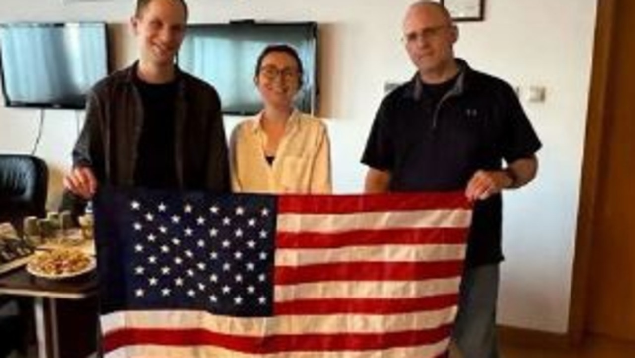 Evan Gershkovich, Alsu Kurmasheva and Paul Whelan hold an American flag after being released in the prisoner swap with Russia. Picture: Supplied