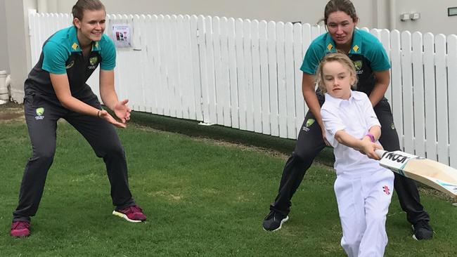 Matisse Easton, 8, unleashes at Allan Border Field at Jess Jonassen(left) and Beth Mooney look on as they prepare to tackle England onSunday.