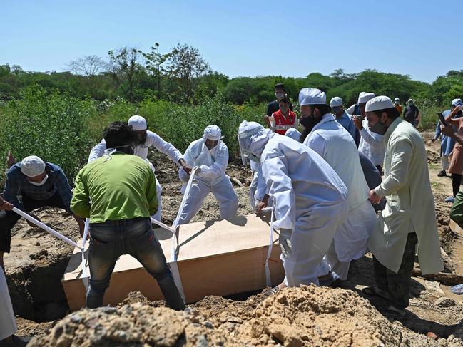 Relatives, family members and cemetery workers lower the casket to bury the body of a patient who died from coronavirus at a graveyard in New Delhi. Picture: AFP