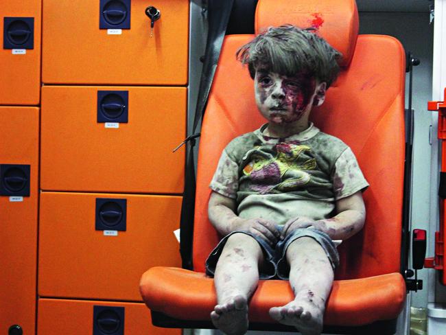 Omran Daqneesh sits alone in the back of the ambulance after he was injured during Russian or Assad regime forces air strike targeting the Qaterji neighbourhood of Aleppo on August 17, 2016. Picture: Mahmud Rslan/Anadolu Agency/Getty Images.