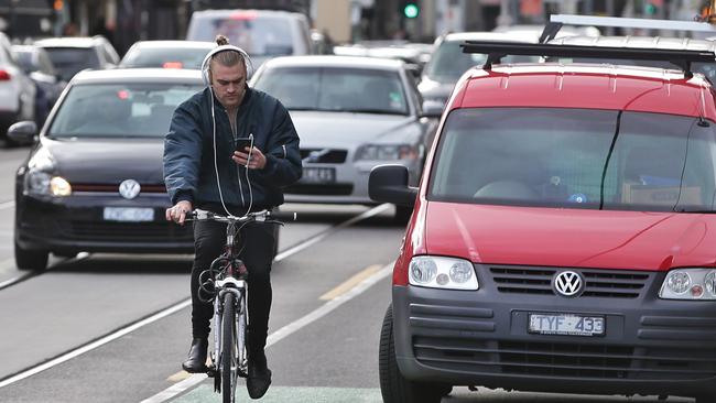 A cyclist on Chapel Street, riding without a helmet, with headphones on and looking at his phone on Thursday. Picture: Hamish Blair