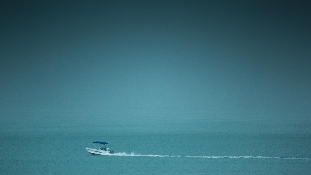 A Darwin fisherman skirts a wall of rain as storms, associated with the oncoming monsoon, in late December. Picture Glenn Campbell