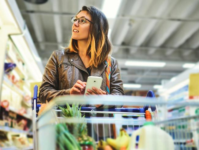 Shot of a young woman using a mobile phone in a grocery store