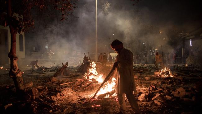 Workers at an Indian crematorium as the number of COVID-19 deaths rises by thousands daily.