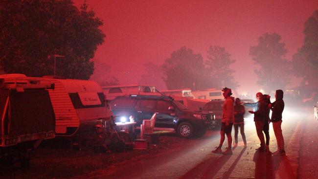 Locals gather in the red haze. Pictures: Trevor Jay