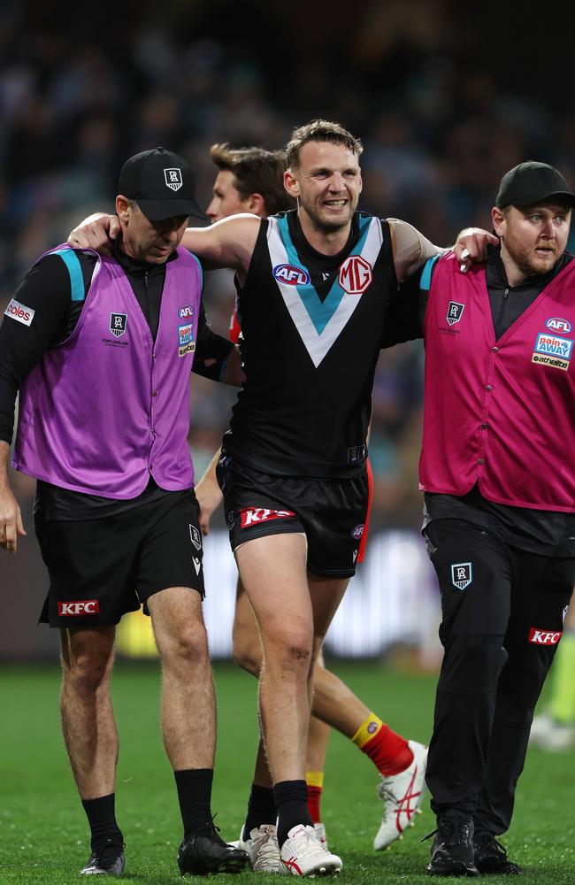 Trent McKenzie is helped from the field. Picture: Sarah Reed/AFL Photos via Getty Images.