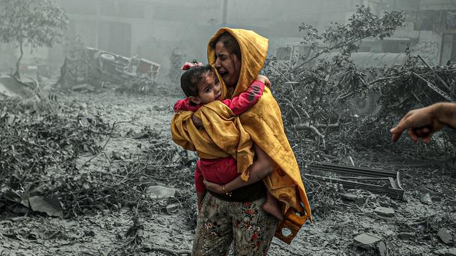 A woman holding a girl reacts after Israeli airstrikes hit the Ridwan neighborhood of Gaza City on Monday. Picture: Getty Images