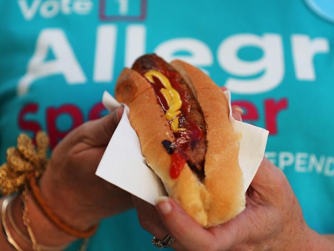 An Allegra Spender supporter holds a 'democracy sausage' at the Clovelly Surf Life Saving Club. (Photo by Lisa Maree Williams/Getty Images)