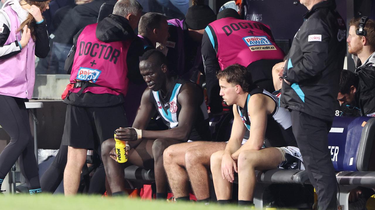 Aliir Aliir of the Power on the bench after a collision with Lachie Jones. Photo by Sarah Reed/AFL Photos via Getty Images.