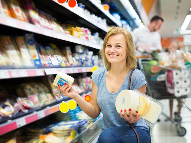 Positive woman holding variety of cheese supermarket