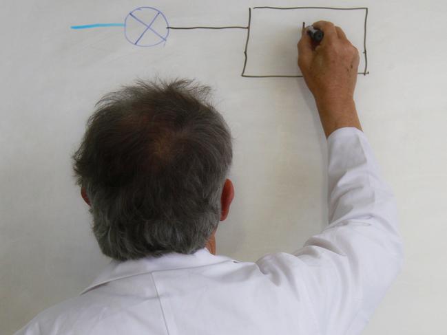 back view of senior teacher writing on white board