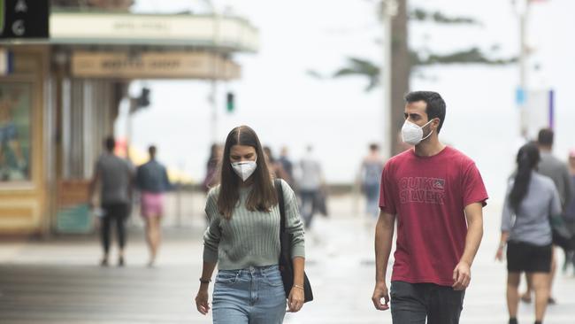 A couple wearing masks walk along The Corso in Manly on January 03, while the northern end of the northern beaches remains under lockdown until 9 January. Picture: Jenny Evans