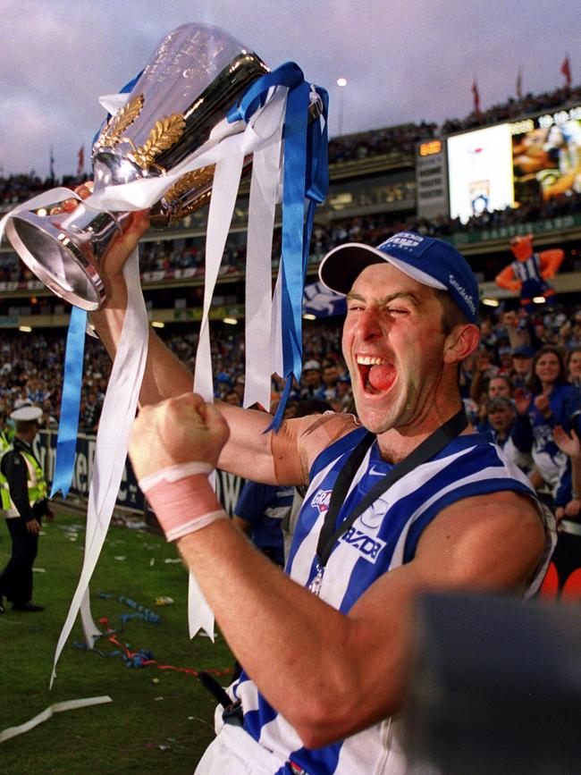 McKernan holding AFL Premiership cup trophy after the Roos beat the Blues in the Grand Final.