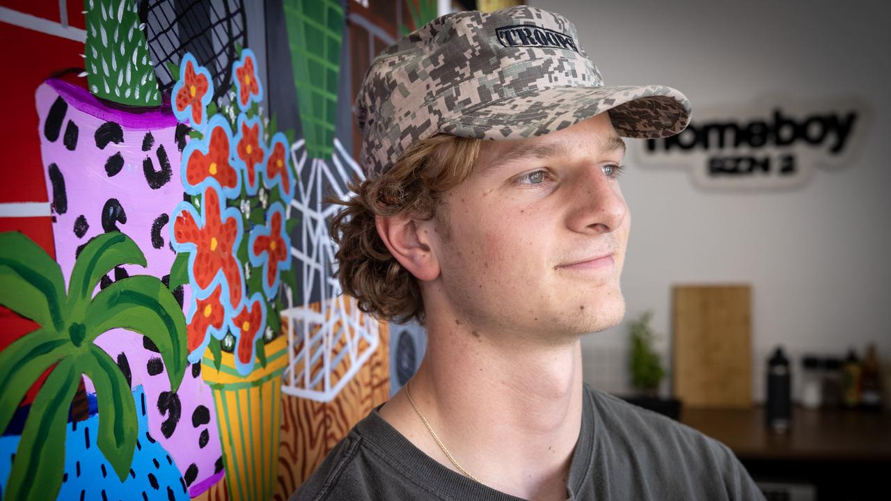 Tom Oswald at his North Terrace cafe, Homeboy, with painting by local artist Adam Tarif. Picture: Emma Brasier