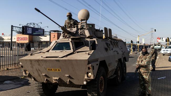 Members of the South Africa Defence Force stand guard with an armoured vehicle outside a mall on the northern outskirts of Johannesburg. Picture: AFP