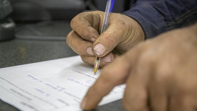 An out of town customer fills out information prior to purchasing alcohol. Picture: Jon Gellweiler/news.com.au