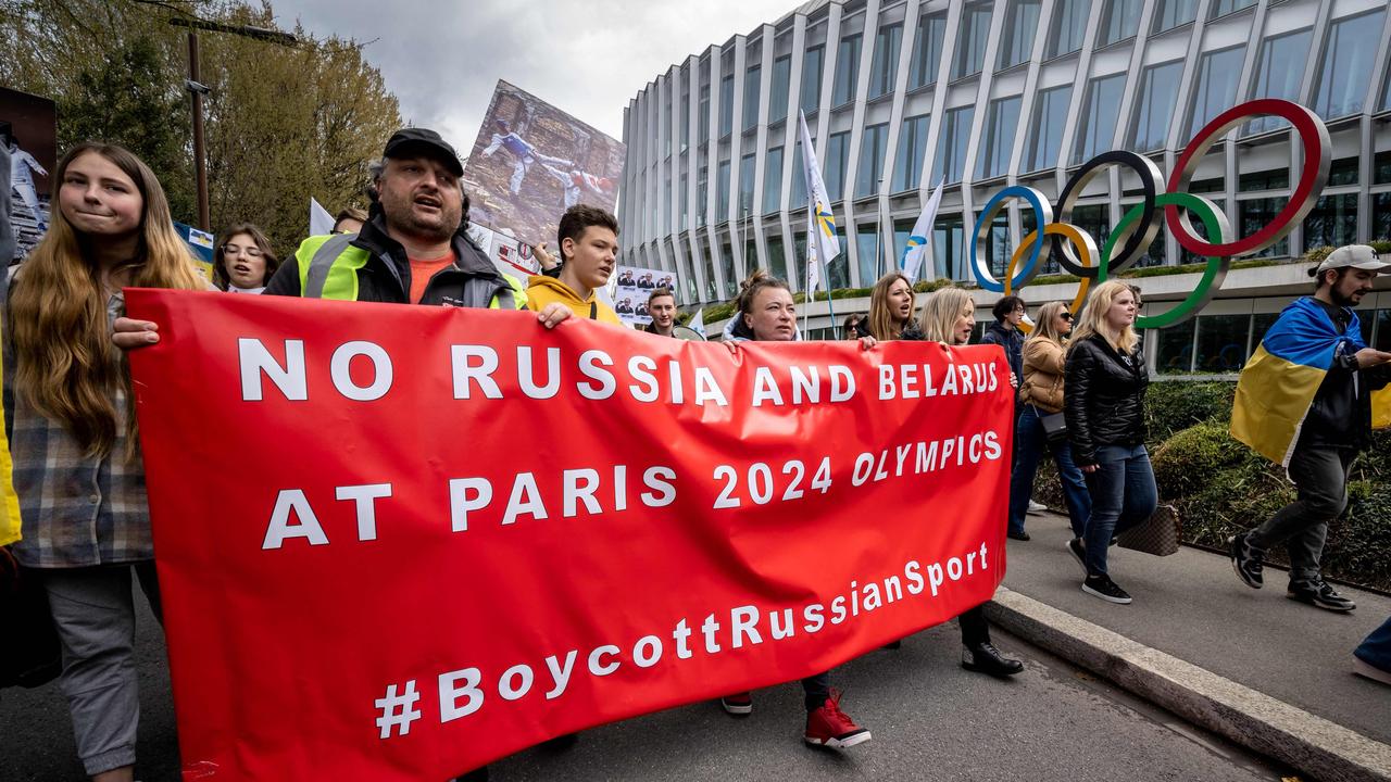 Ukrainians walk past the headquarters of International Olympic Committee (IOC) during a protest against the proposed IOC roadmap to organise the return to competition of Russian athletes under a neutral flag, provided that they have "not actively supported the war in Ukraine" in Lausanne on March 25, 2023. (Photo by Fabrice COFFRINI / AFP)