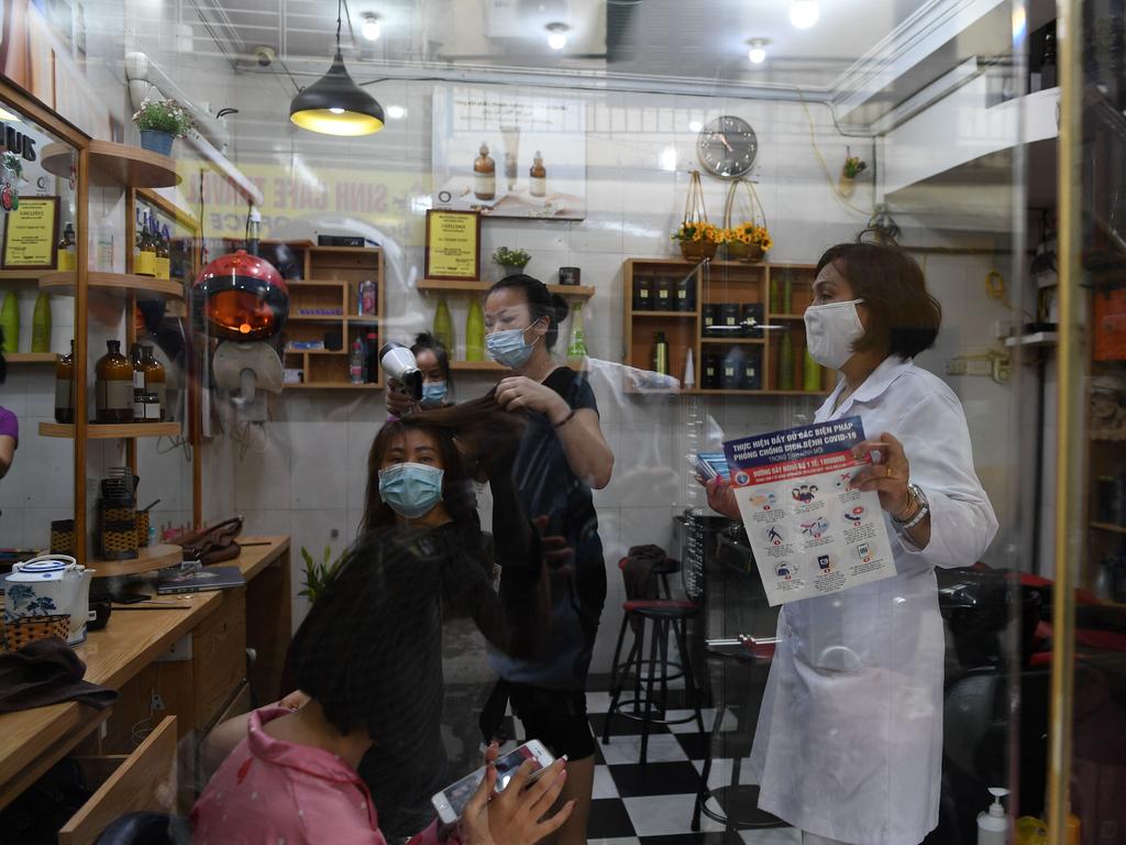 A local health officer (R) advises hair salon staff in Hanoi on May 25, 2021 to close, as city authorities expanded closure orders. Picture: Nhac Nguyen/AFP